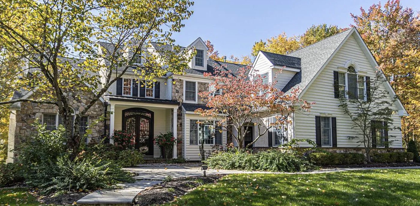 Arboresque — a large stone-and-siding home framed by autumn trees