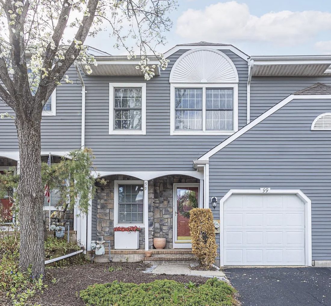 Greenbrook — a grey-blue townhome with stone accents and spring blossoms